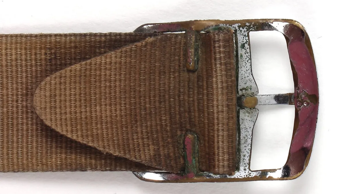 The buckle end of a woven watch strap in close up